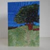Front view of greetings card showing oak tree in summer foliage near top of grassy hillside.