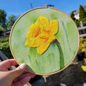 Bright yellow single daffodil hand embroidered on watercolour background 6 inch hoop wall hanging.