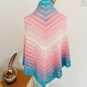 Crochet triangle scarf in the blue, pink, and white stripes of the Transgender Pride flag, draped to show its full shape made by Sarah Lou Crafts.