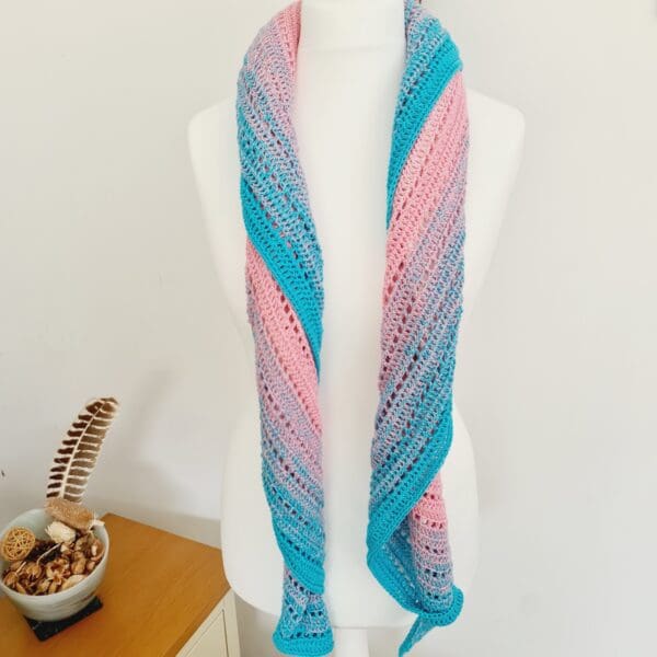 Textured shot of a crochet triangle scarf in Transgender Pride colours, highlighting the intricate stitches and soft yarn, made by Sarah Lou Crafts.