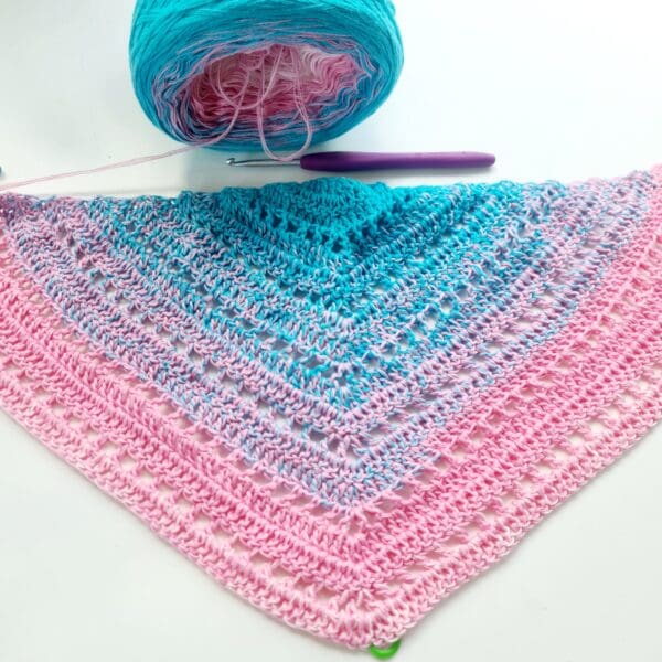 Close-up of a handcrafted crochet shawl featuring the horizontal stripes of the Transgender Pride flag: light blue, pink, and white. Made by Sarah Lou Crafts.