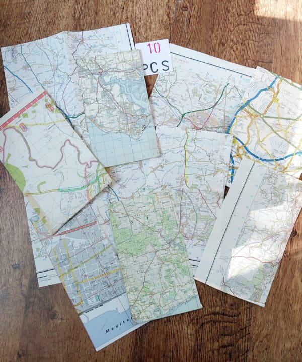 A collection of irregularly shaped map pieces scattered on a table, featuring different colours and patterns from various maps.