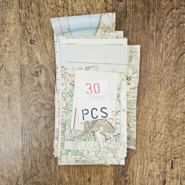 A shot of a pile of curated scraps of various maps, focusing on the texture of the paper and irregular sized pieces.