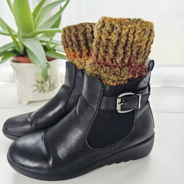 A full-length shot of a pair of black ankle boots with crochet boot cuffs in autumn colours are visible at the top of the boots