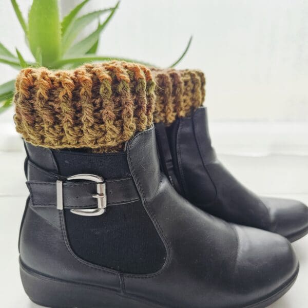 A pair of crochet boot cuffs shown being worn wearing a pair of black ankle boots.