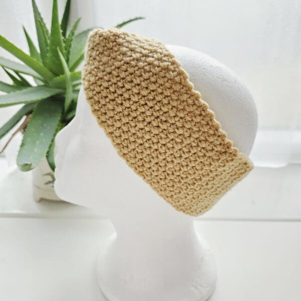 Handmade sand crochet headband displayed on a white mannequin, highlighting its width and warmth.