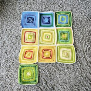 Crochet squares with different coloured rows in Blues, greens, yellows, orange and reds to show the top temperature taken at 12 pm each day in Carmarthenshire, Wales for the months of January to October 2025.
