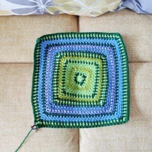 November temperature blanket square in rows of greens, blues and a lavender purple row. 