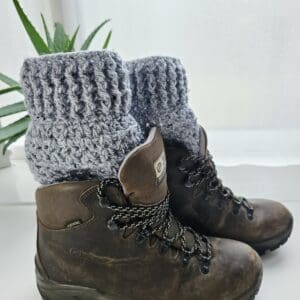 Crochet boot cuff in Marble Grey aran yarn, close-up view showing the textured stitch, worn extending from the top of a brown hiking boot.