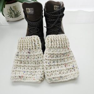 A close-up shot of the top of a brown hiking boot, showing a ribbed, nougat cream crochet boot cuff with a v-stitch pattern.