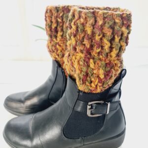 A stylish pair of black ankle boots and russet-coloured crochet boot toppers. The photo emphasises the thick, warm quality of the aran yarn and its suitability for chilly weather.
