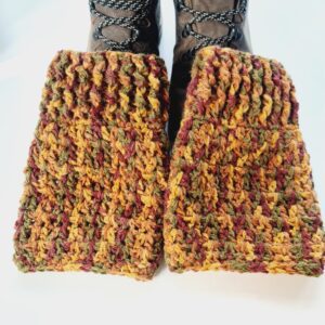 A lifestyle shot from above, showing autumn russet crochet boot cuffs styled with brown hiking boots. The chunky knit texture adds a cosy, layered look for outdoor walks.