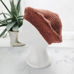 The side and brim of a handmade orange merino beret, showing the stretchy ribbed edge designed for comfort. The deep ginger hue of the wool looks soft and non-itchy.