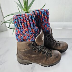 Side view of colourful woollen boot cuffs showing the intricate crochet stitch pattern, tucked into dark brown lace-up hiking boots.