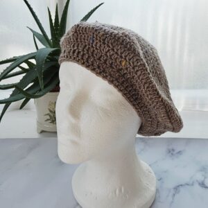 Side profile of the Acorn merino wool beret, showing the soft drape and slouchy silhouette of the crochet fabric against a plain white mannequin.
