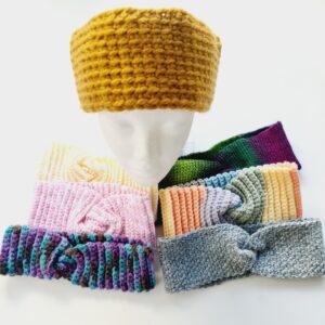 A group photo showing the range of crochet headbands arranged around a white mannequin head wearing a gold ear warmer.