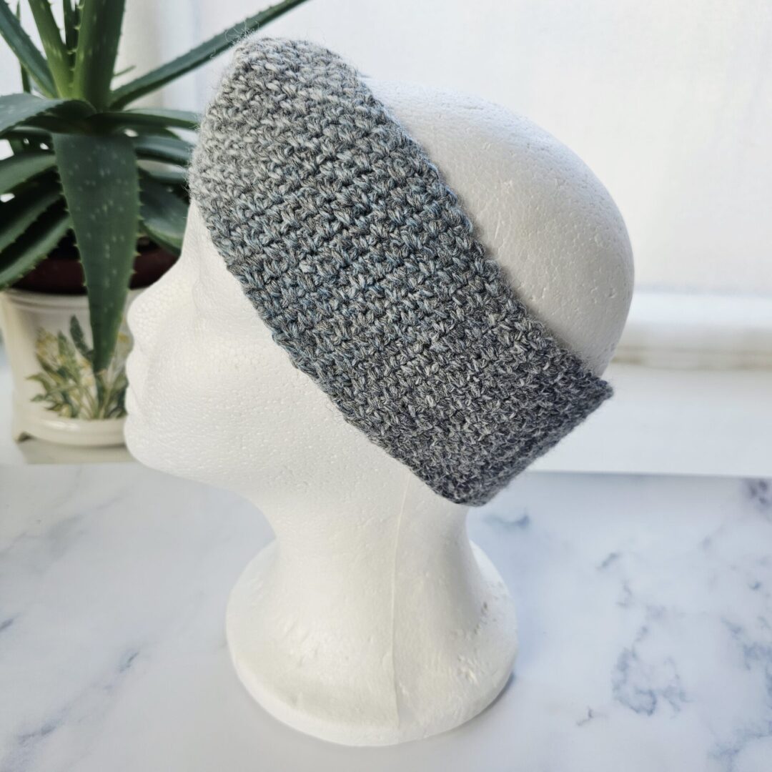 A detailed close-up of the marble grey crochet fabric. The image shows the variegated yarn with flecks of charcoal and silver, highlighting the high-quality hand-stitched loops and soft, bulky finish.