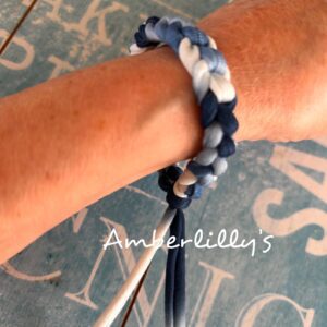Tie dye style blue and white t shirt yarn crochet bracelet worn by creator with a blue background