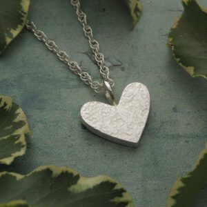 Handmade solid sterling silver heart hammered with silk texture shown on a silver rope chain